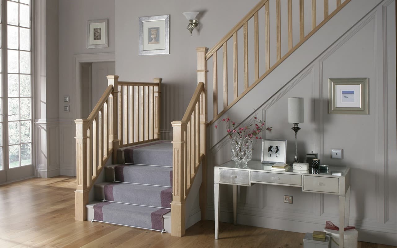 Oak staircase with a grey stair runner and turned spindles in a bright hallway